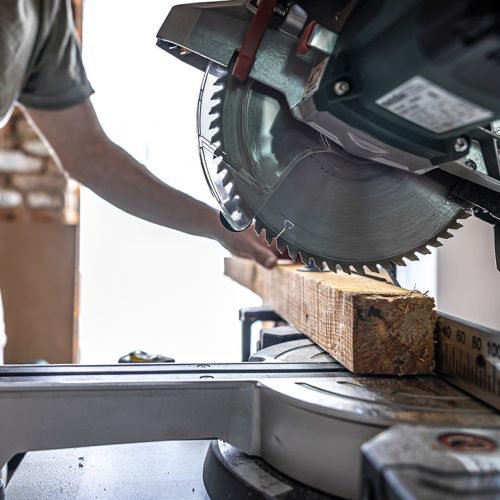 A professional carpenter works with a circular saw miter saw in a workshop.